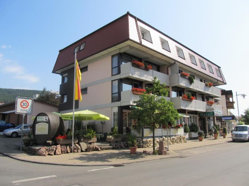 Hotel Gasthof Hirschen with balconies, outdoor seating, and a large barrel sign.