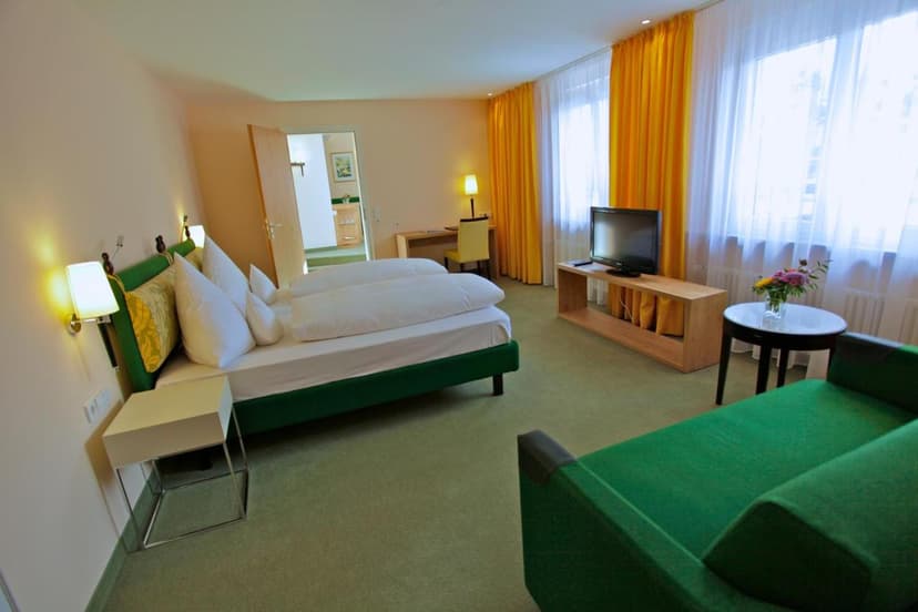 Parkhotel Flora am Schluchsee room with green bed and yellow curtains.