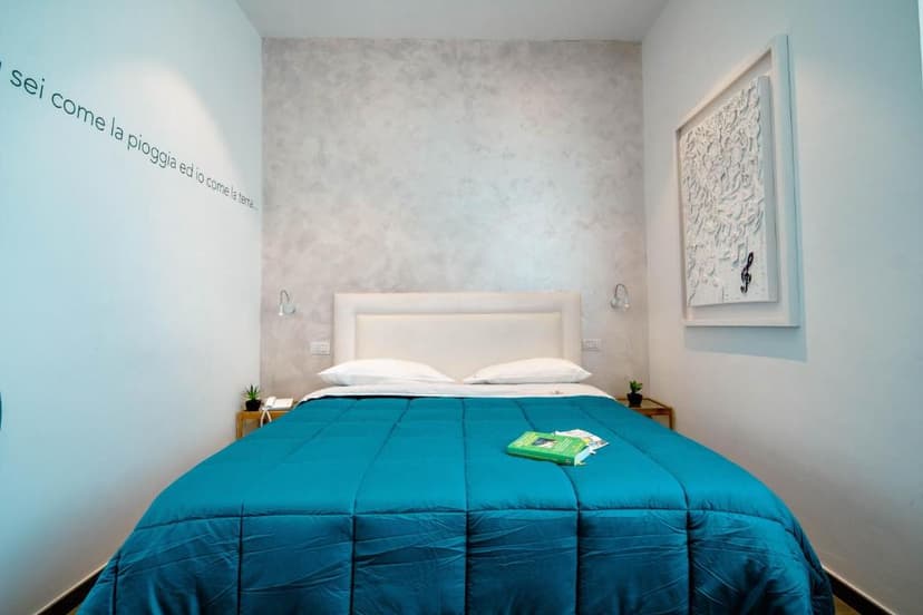 Bedroom with white walls, teal comforter, and modern white artwork with a treble clef.