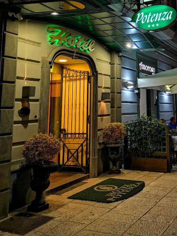 Hotel Potenza entrance at night with green illuminated sign and doormat