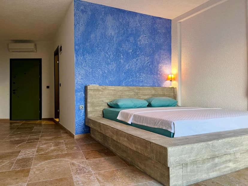 Hotel room with wood platform bed, textured blue accent wall, and tiled floor