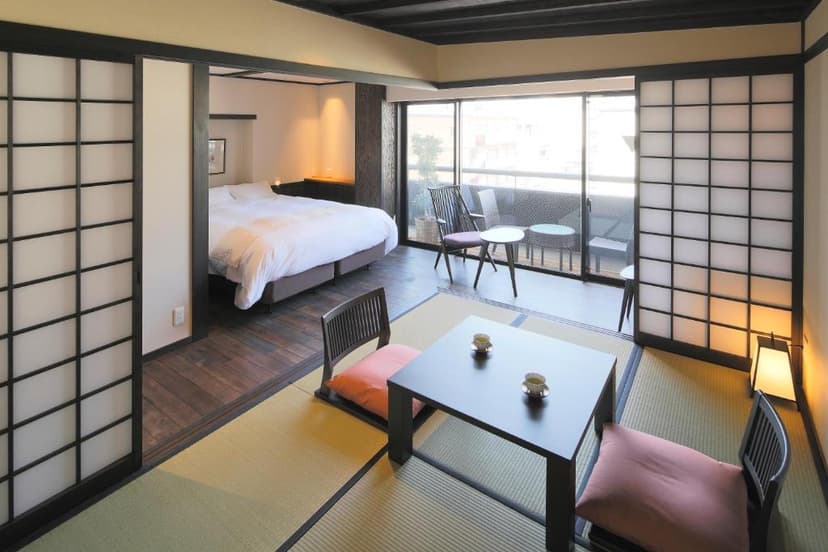 Japanese ryokan room with tatami seating area, low table with tea, and separate modern bedroom.