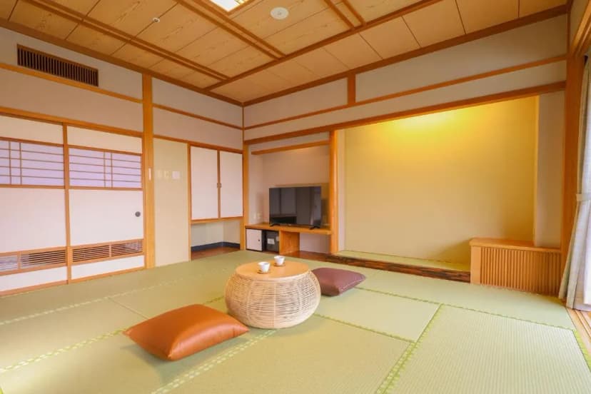 Traditional Japanese room with tatami mats, low wicker table, and television in Kisoji.