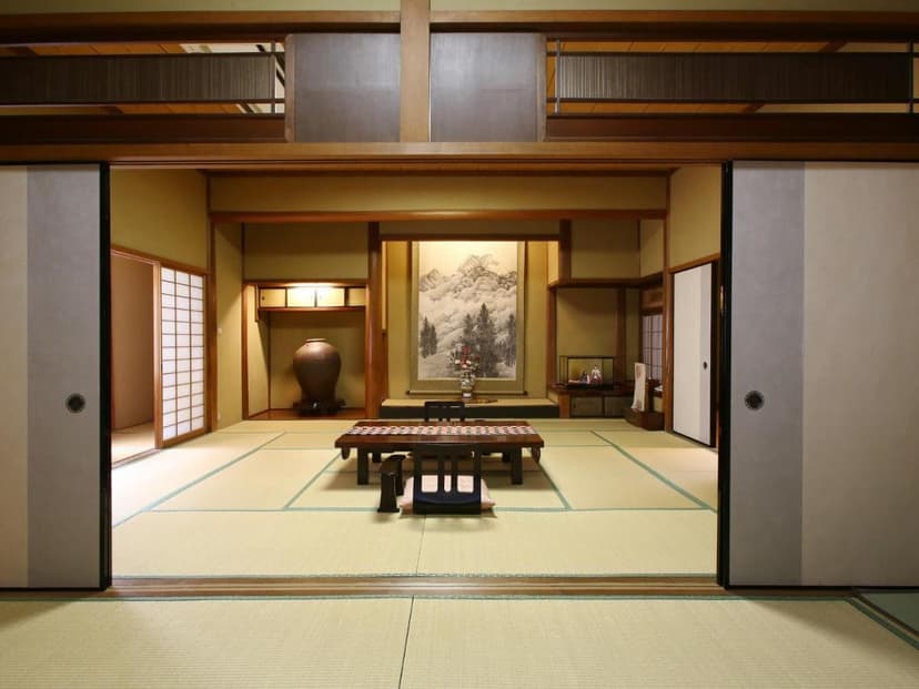 Traditional Japanese room with tatami mats, low table, and mountain scroll art at Kisoji-no-Yado Iwaya.