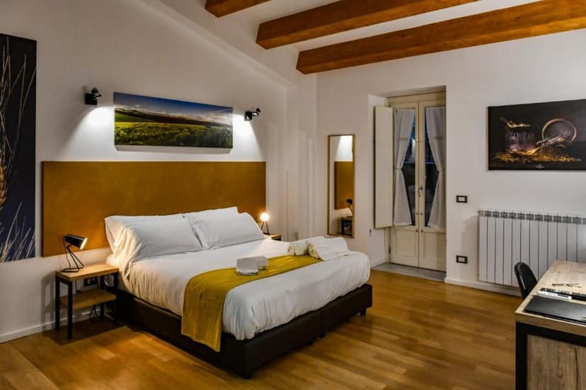 Bedroom in Ballarooms B&B Palermo Centro with wood beams, white linens, and wood floors.