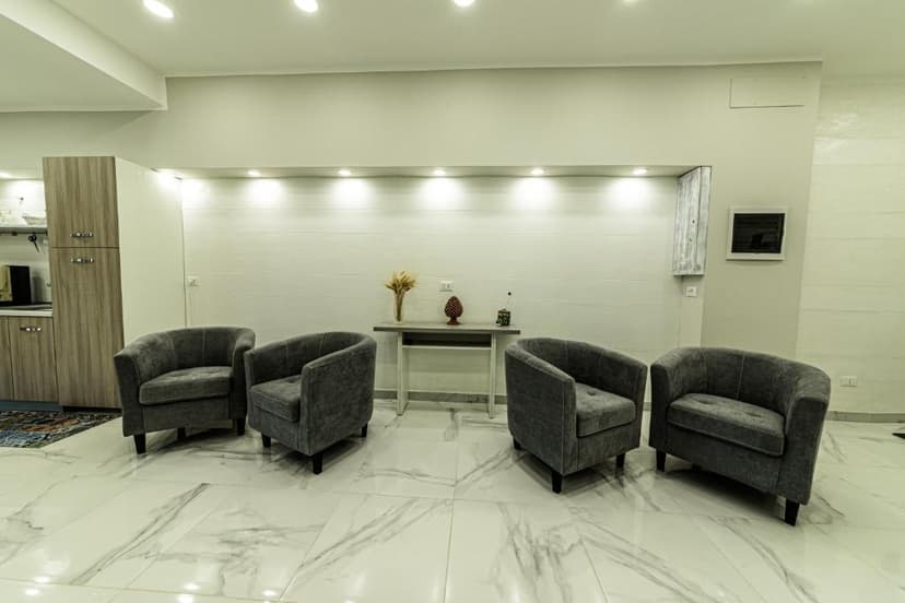 Four grey velvet armchairs in a modern waiting area with white marble floors.