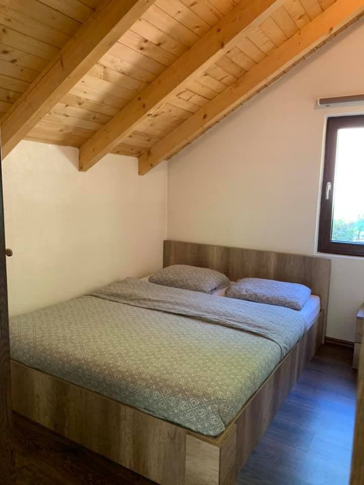 Bedroom with wooden sloped ceiling, wood-look bed frame, and patterned bedding.