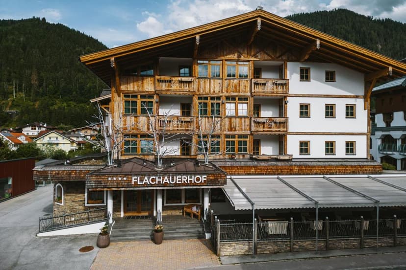 Hotel Flachauerhof with wooden balconies against a backdrop of forested mountains.