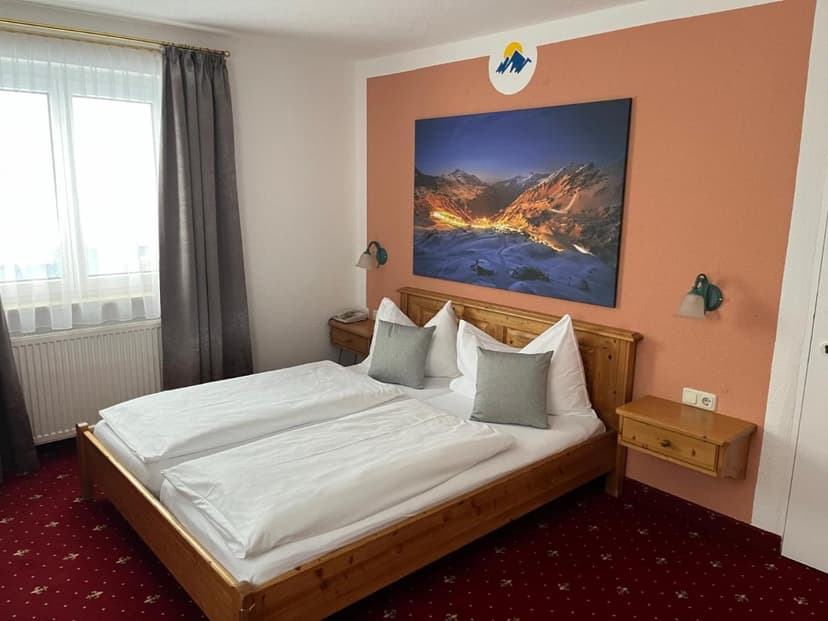 Hotel Solaria twin room with wooden bed, white linens, and mountain artwork.