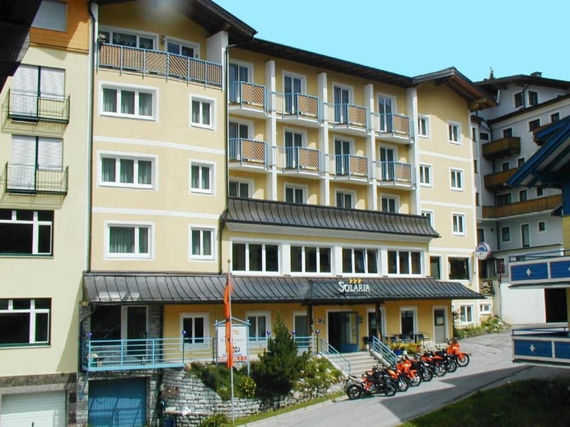 Hotel Solaria building exterior with row of parked orange motorcycles on sloped road