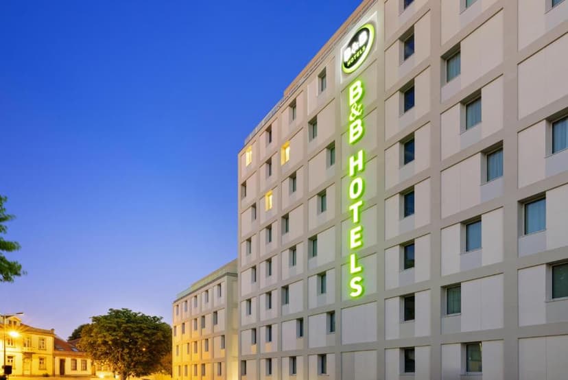 B&B Hotel Porto Centro Massarelos exterior facade with green neon sign against a blue twilight sky.