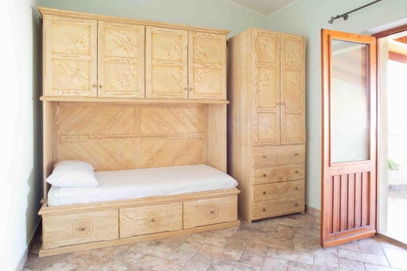 Light wood built-in bed unit and wardrobe next to open glass door in room