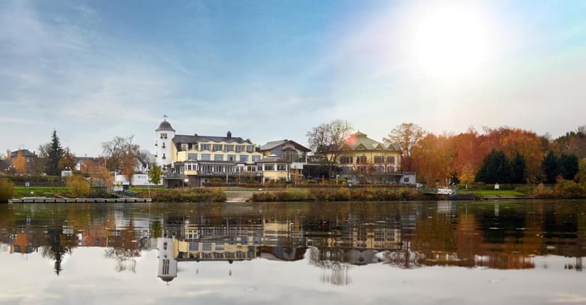 Hotel Weisser Bär reflected in water with autumn trees and bright sun