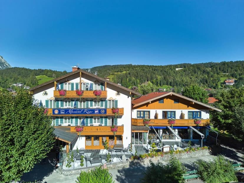 Alpenhotel Rieger building with balconies and flower boxes against forested alpine hillsides