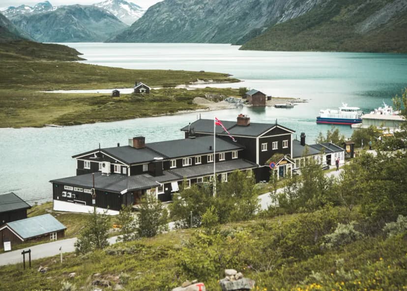 Gjendesheim Hut by lake with mountains and ferry boat, Norway