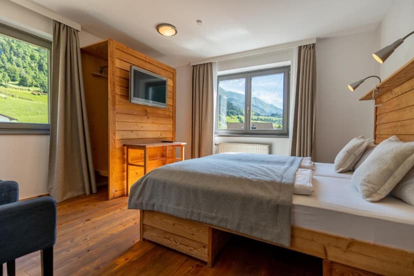 Hotel room with wooden accents and view of green mountains through windows