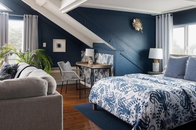 Bedroom with navy walls, wood floors, and a bed with blue octopus print duvet.
