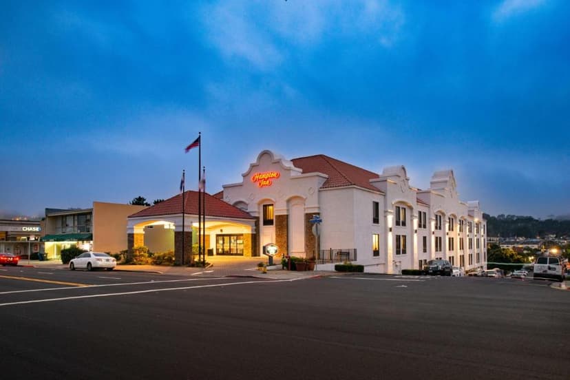 Hampton Inn San Francisco - Daly City hotel exterior with illuminated entrance at dusk.