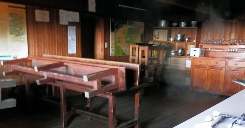 Interior of Refuge de Ciottulu di i Mori with wooden walls and stacked tables.