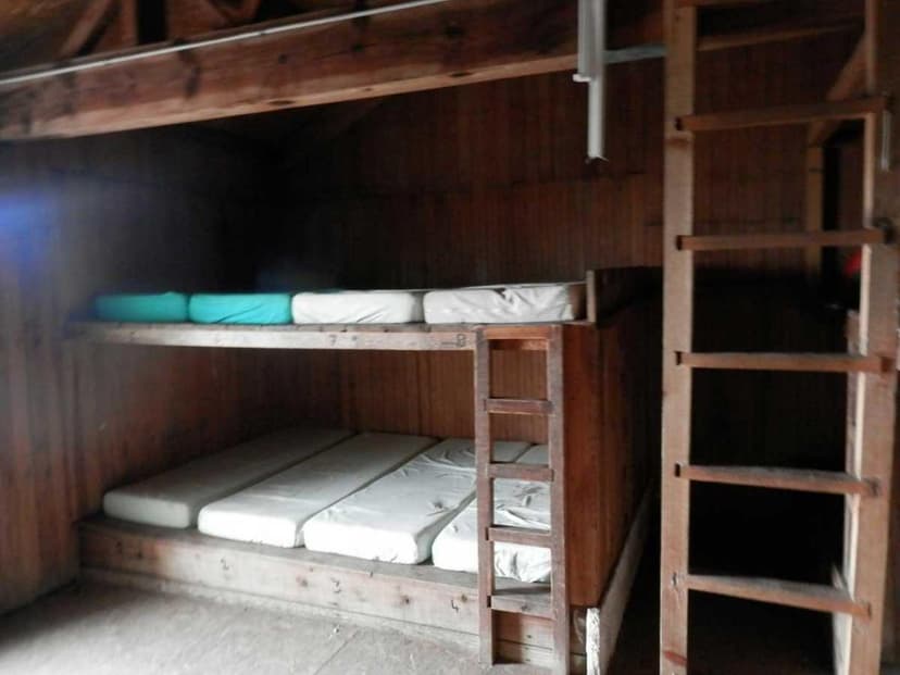 Wooden bunk beds with mattresses inside a rustic refuge or cabin at Refuge de Manganu.