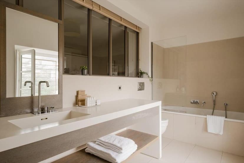 Modern bathroom with white vanity, sink, mirror, and built-in bathtub area.