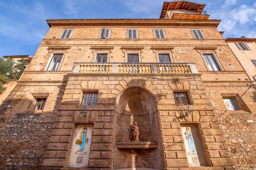 HOTEL TREVI Palazzo Natalini facade with arched niche, statue, and tiled artwork under blue sky.