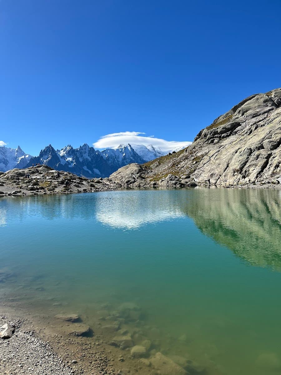 Alpine lake with turquoise water reflecting snow-capped mountains under a clear blue sky.