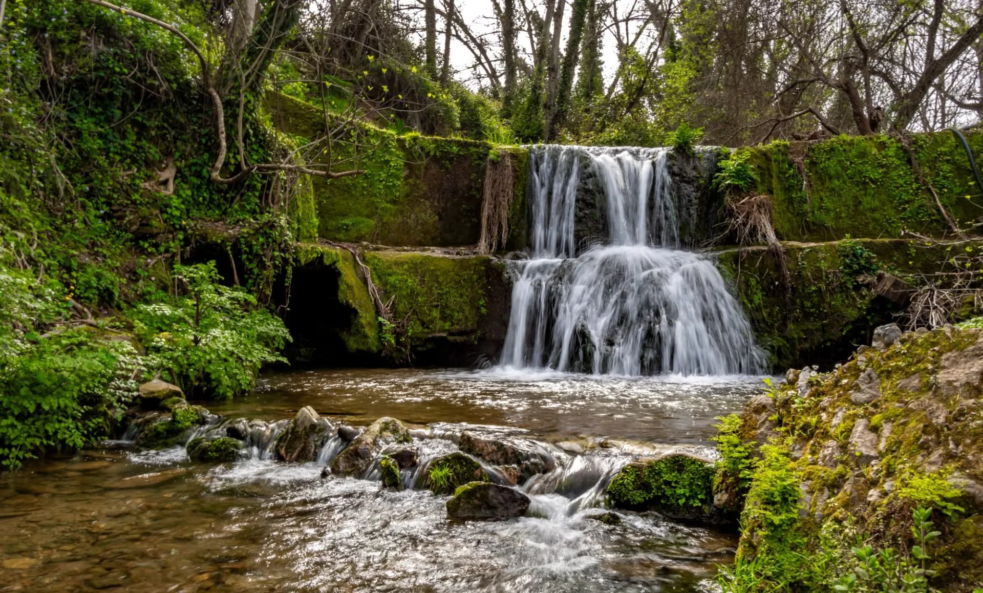Cascada de los Molinos waterfall surrounded by lush green moss and forest in Corteconcepción, Huelva, Andalucía.