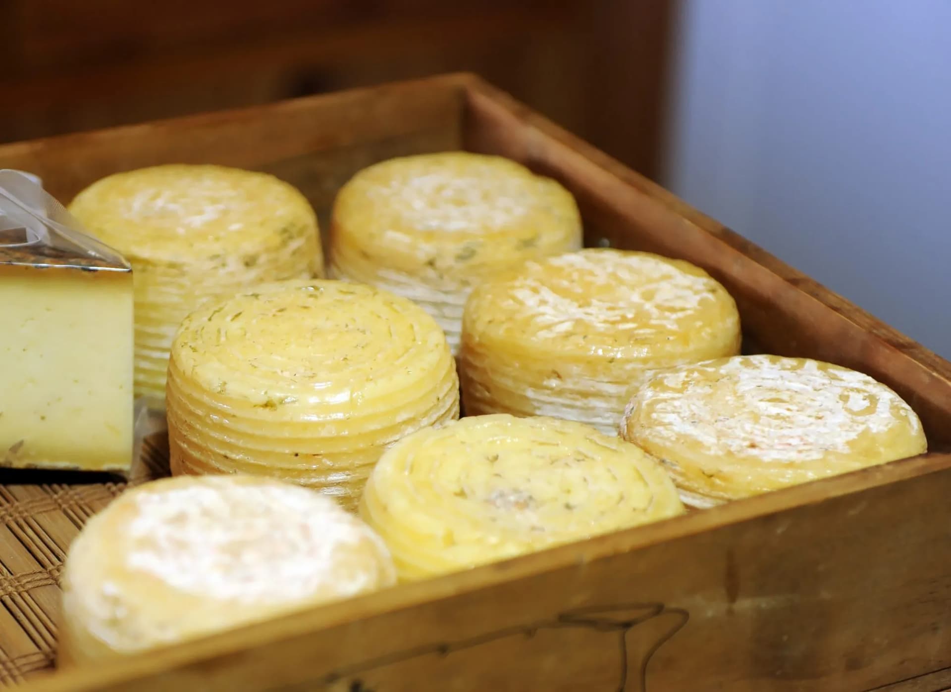 Rounds of Queso de Cabra Payoya cheese in a wooden crate at a market