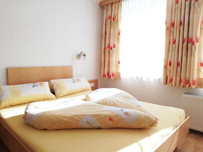 Bedroom in Gasthof Ködnitzhof with yellow bedding and tulip-patterned curtains.