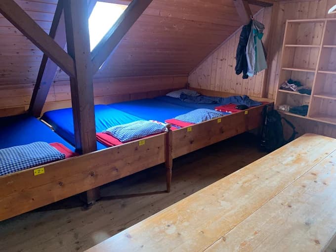 Wooden bunk room with blue mattresses, pillows, and a long wooden table in Gleiwitzer Hütte.