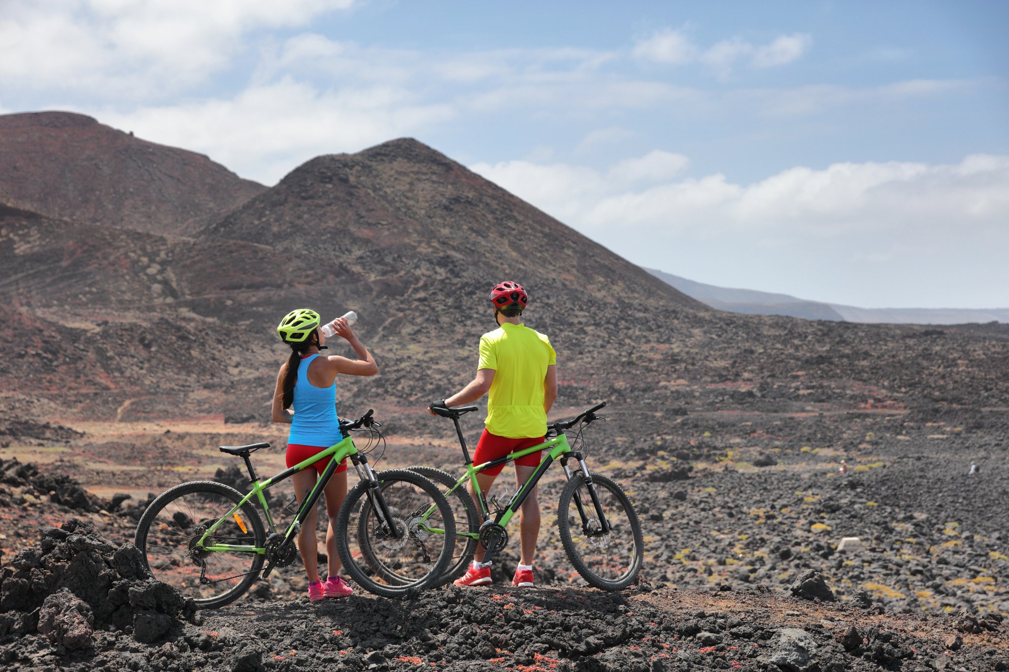Avventura in bicicletta su paesaggio vulcanico estremo. Due ciclisti in tour di gruppo guidato durante le vacanze estive a Lanzarote, Isole Canarie, Spagna.