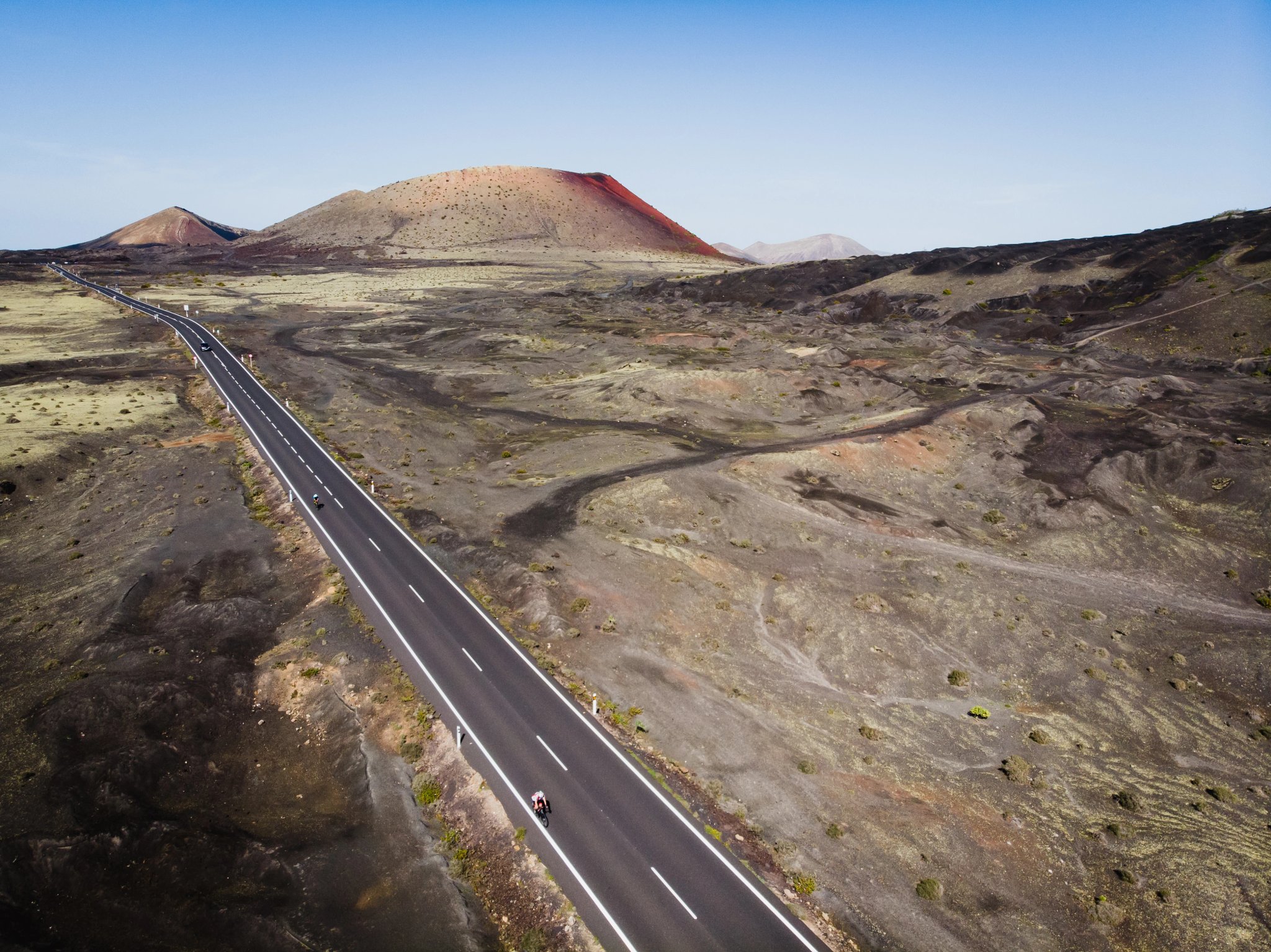 Un ciclista percorre una strada tra crateri vulcanici, Isola di Lanzarote, Spagna.