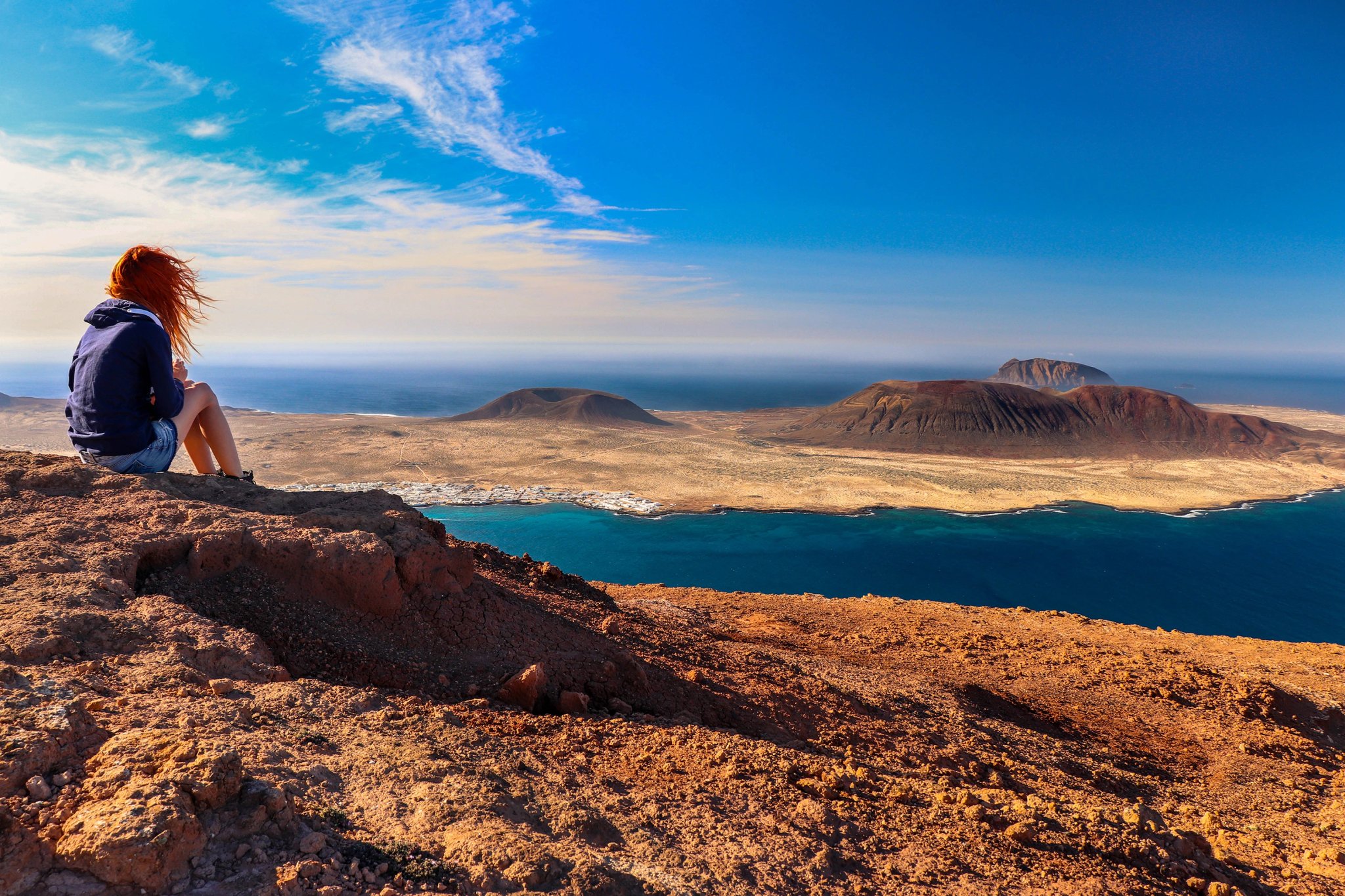 Una donna che guarda il mare e l'isola. Luogo: Europa, Spagna, Isole Canarie, Lanzarote (vicino a Mirador del Rio; isola La Graciosa sullo sfondo)