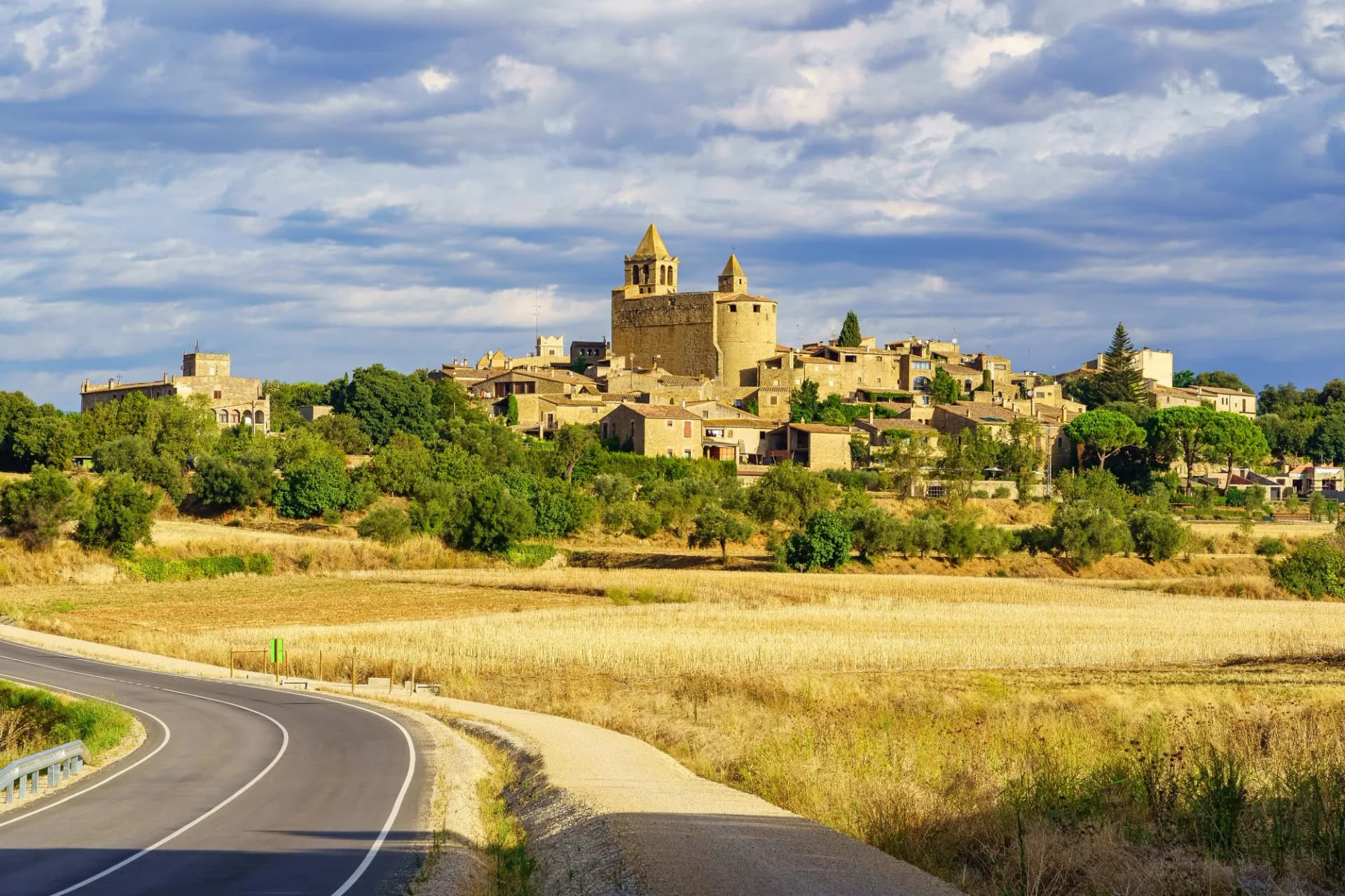 Panoramic view of the medieval village of Madremanya in Girona, Catalonia, Spain, with dry fields and road.