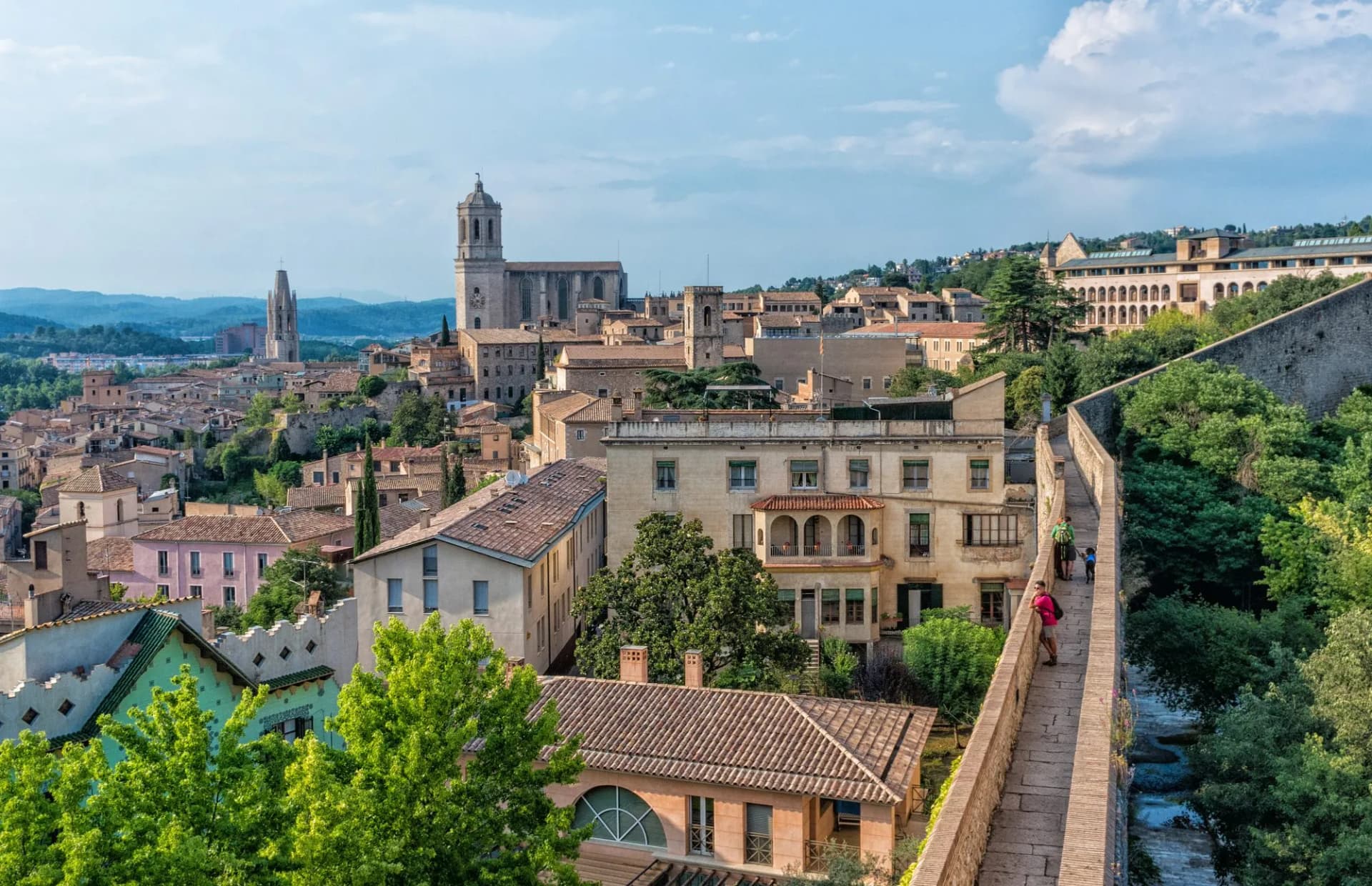 View of the Cathedral in Girona, Spain, from ancient city walls overlooking terracotta roofs.