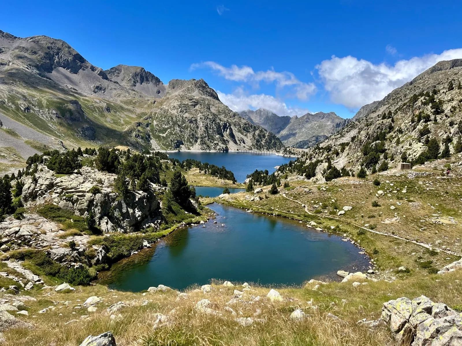 Ibon de Campo mountain lakes in the Pyrenees under a blue sky with scattered clouds.
