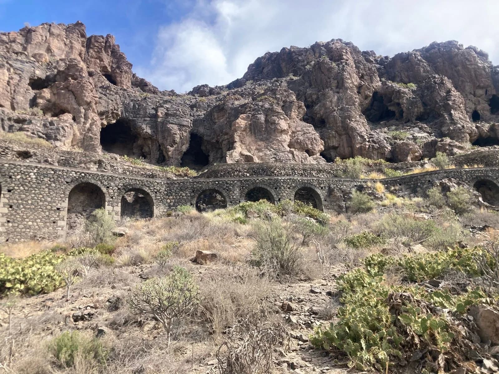 Stone arches retaining wall below caves in arid mountains, Gran Canaria.