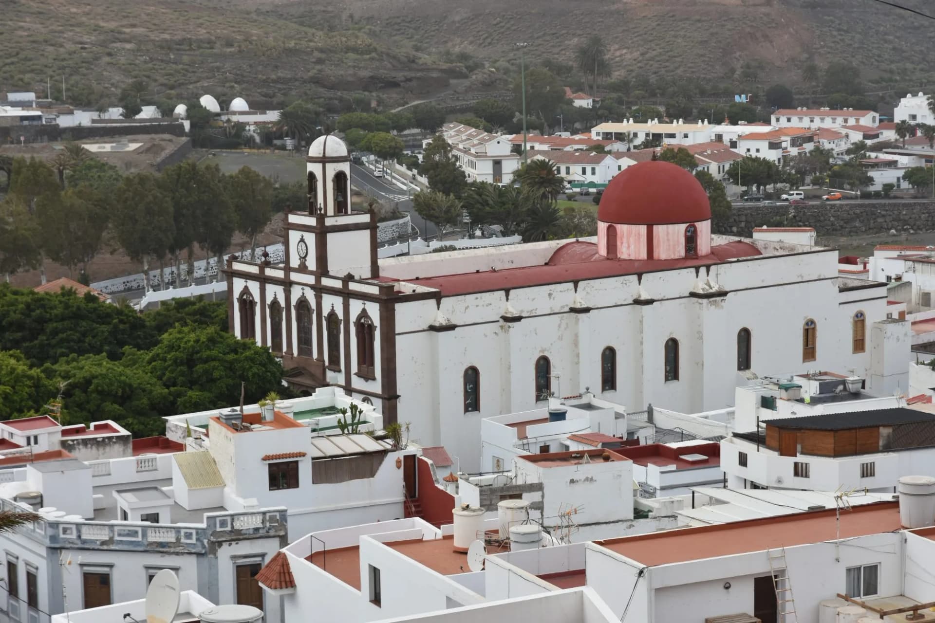 White church with red dome and bell tower overlooking town rooftops in Agaete, Gran Canaria.