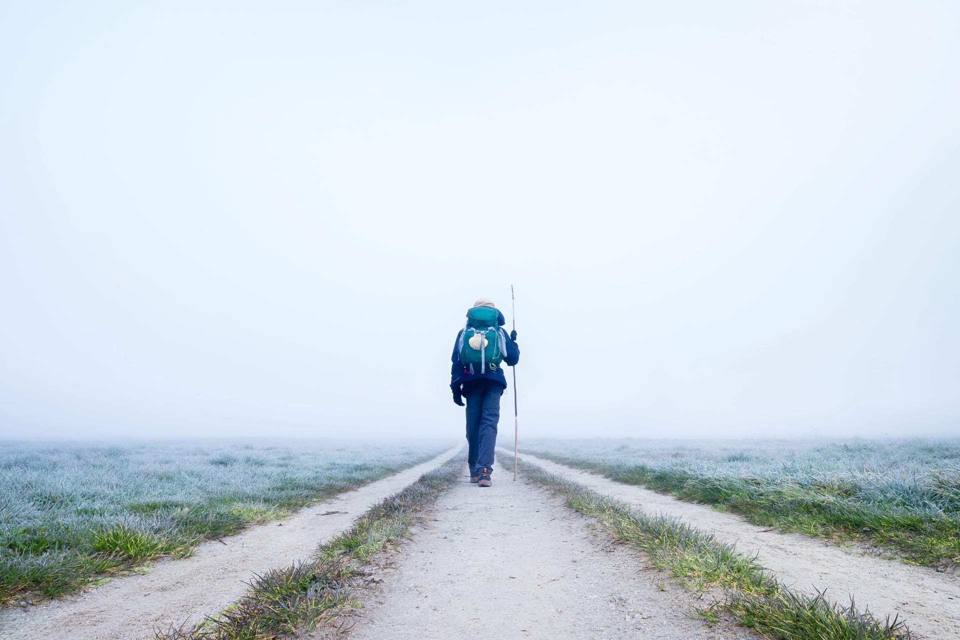 A Lone Pilgrim Girl Hiker Walking off into the Frosty Morning Fog on the Way of St James Pilgrimage Camino de Santiago