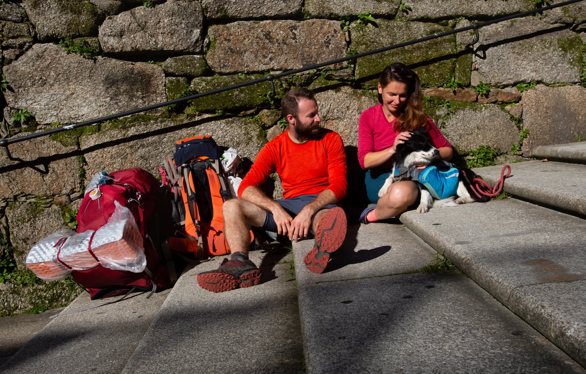Two pilgrims finish the Camino de Santiago and rest on the steps of Plaza del Obradoiro in front of the Cathedral of Santiago de Compostela