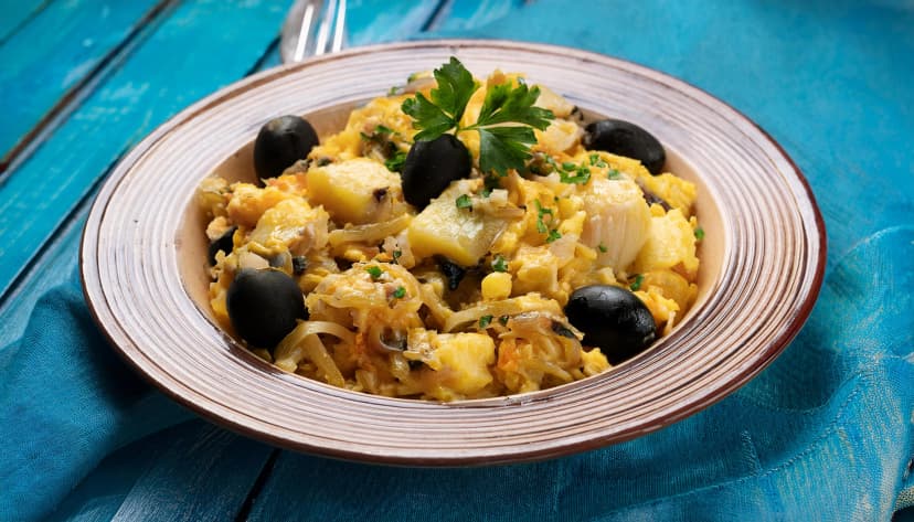 A plate of Bacalhau à Brás, a traditional Portuguese dish made from shredded salted codfish, mixed with crispy potatoes, onions, and scrambled eggs.