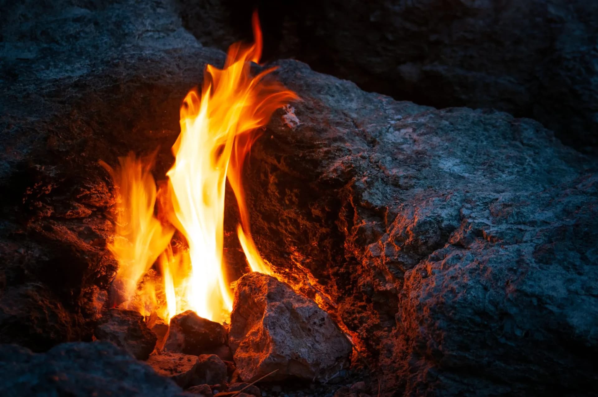 Bright orange flames erupting from rocks at night, referencing the Eternal Flames of the Chimaera.