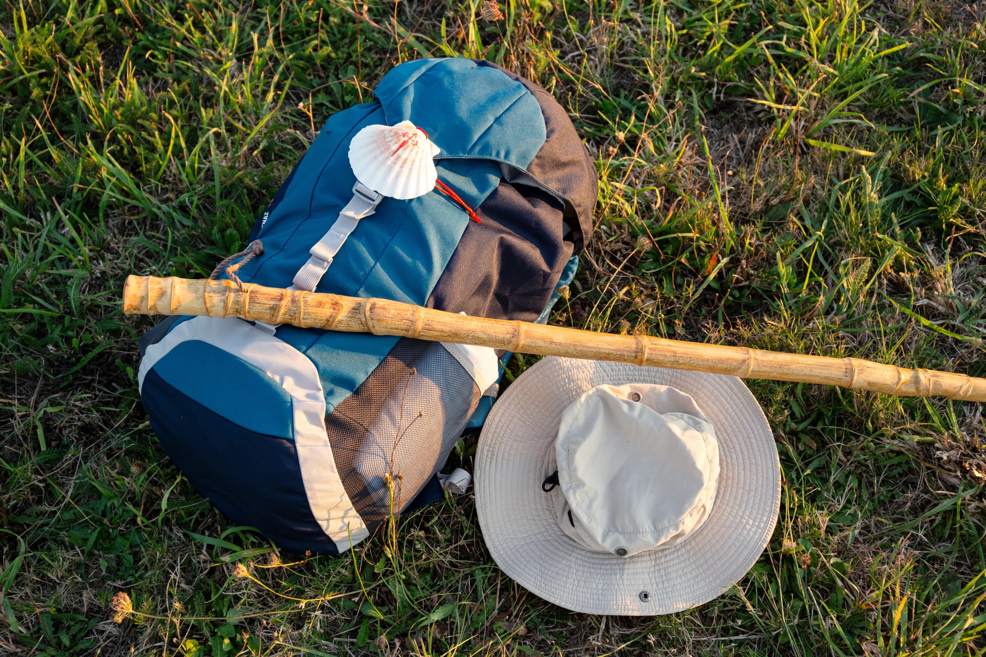 Backpack, hat and walking stick lying on grass during Camino de Santiago pilgrimage