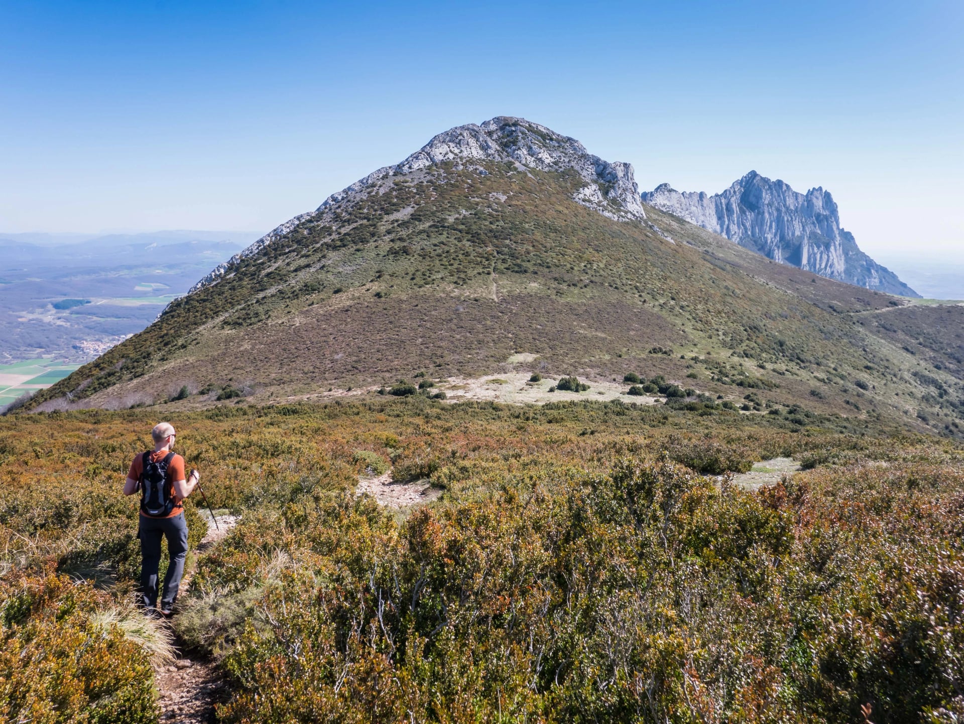 Male hiker descending a mountain and view over peak Recilla in the Cantabria mountain range between La Rioja and Alava, Basque Country, Spain