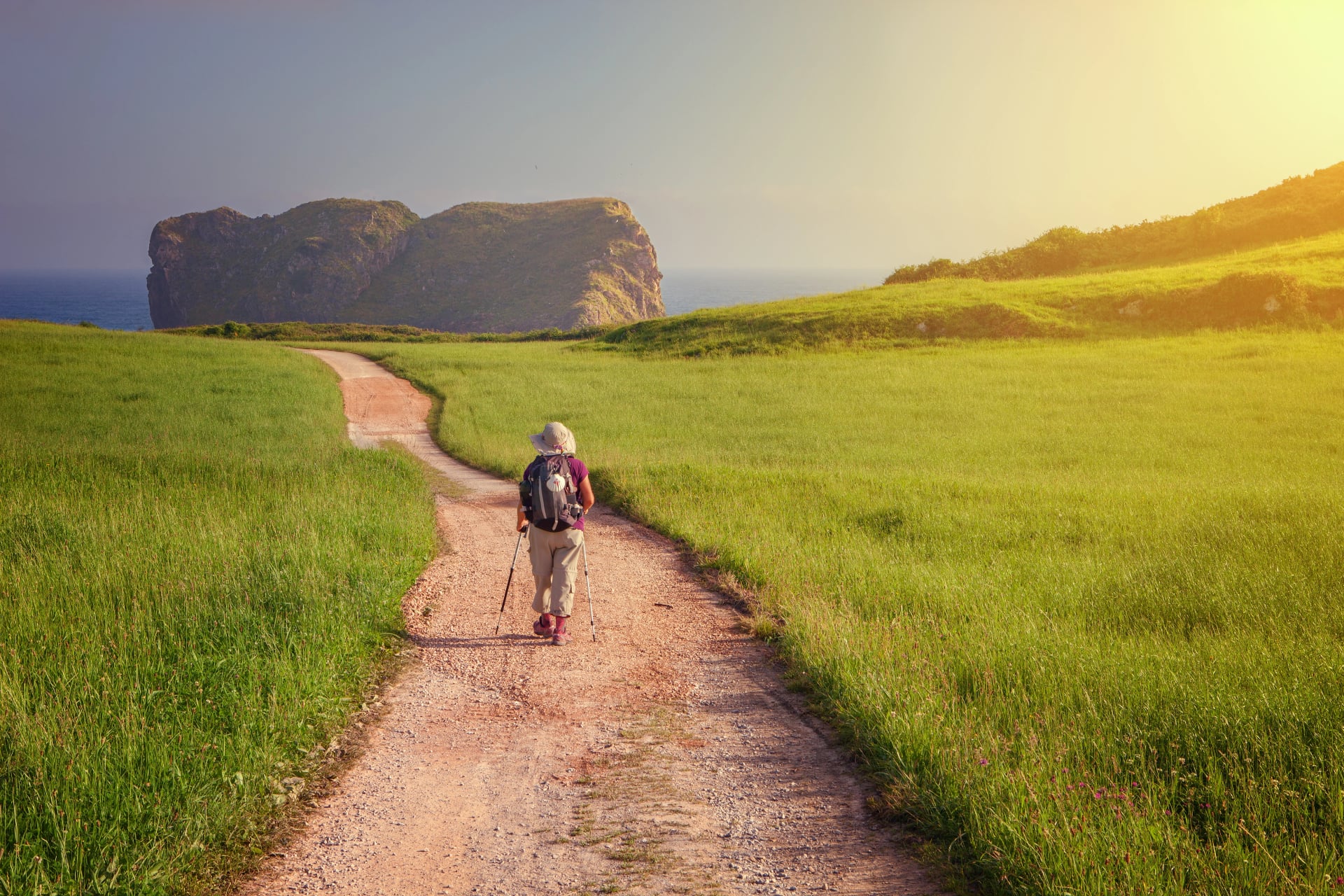Pilgrim walking towards St. Martin church on the coast of LLanes to beach of the Camaras, Asturias, Spain