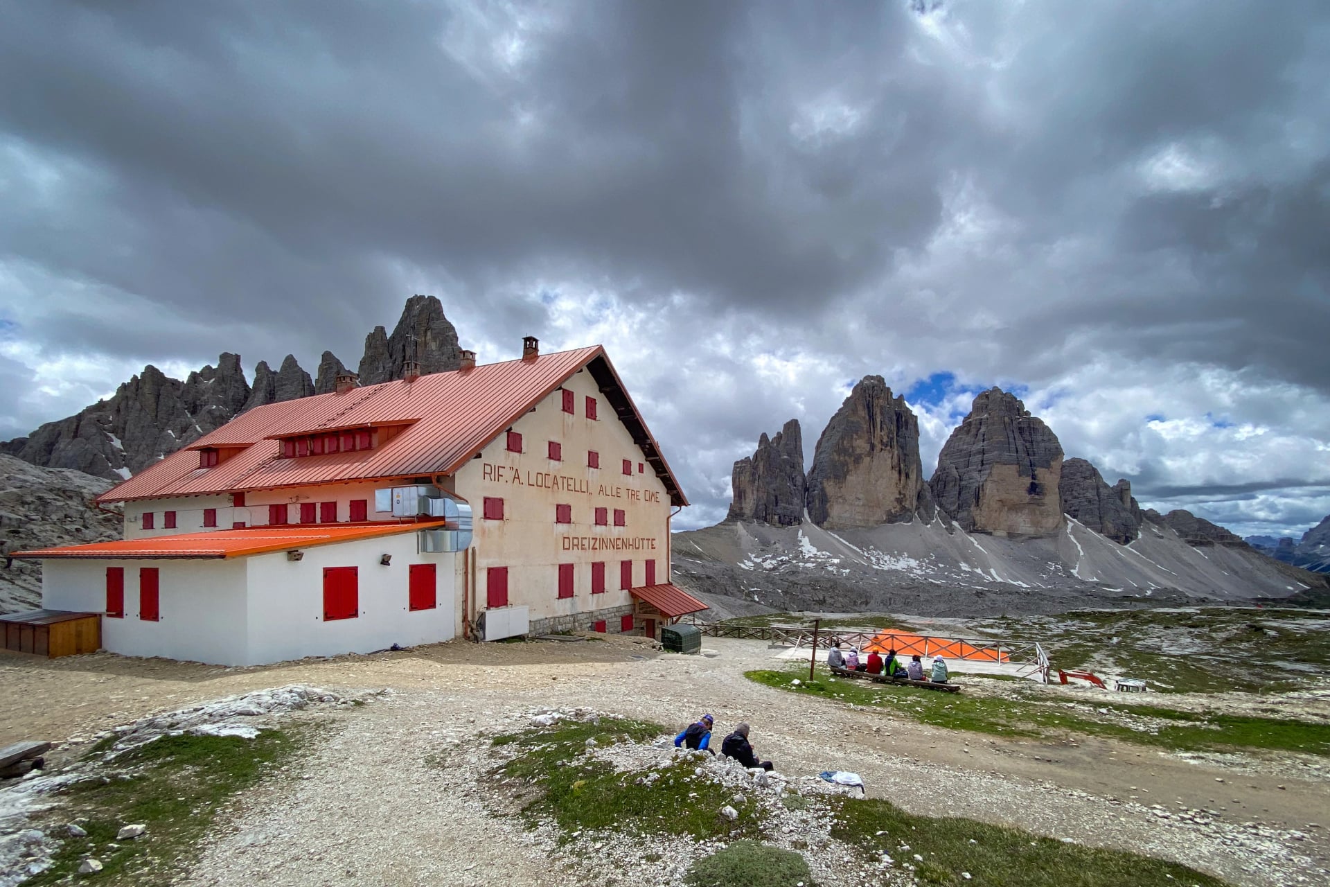 Scenic view of the Dreizinnenhütte (Rifugio A. Locatelli – S. Innerkofler), Italy with Tre Cime di Lavaredo beyond; mountain hut from 1935 with red shutters against cloudy sky