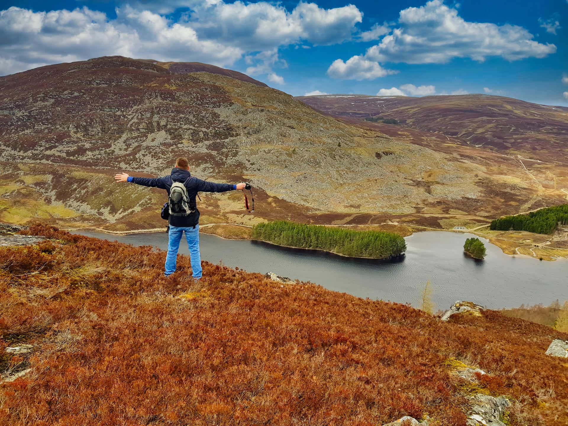 Man raising hands open arms. Explore to highland mountain,man facing to a lake in the scottish highlands.