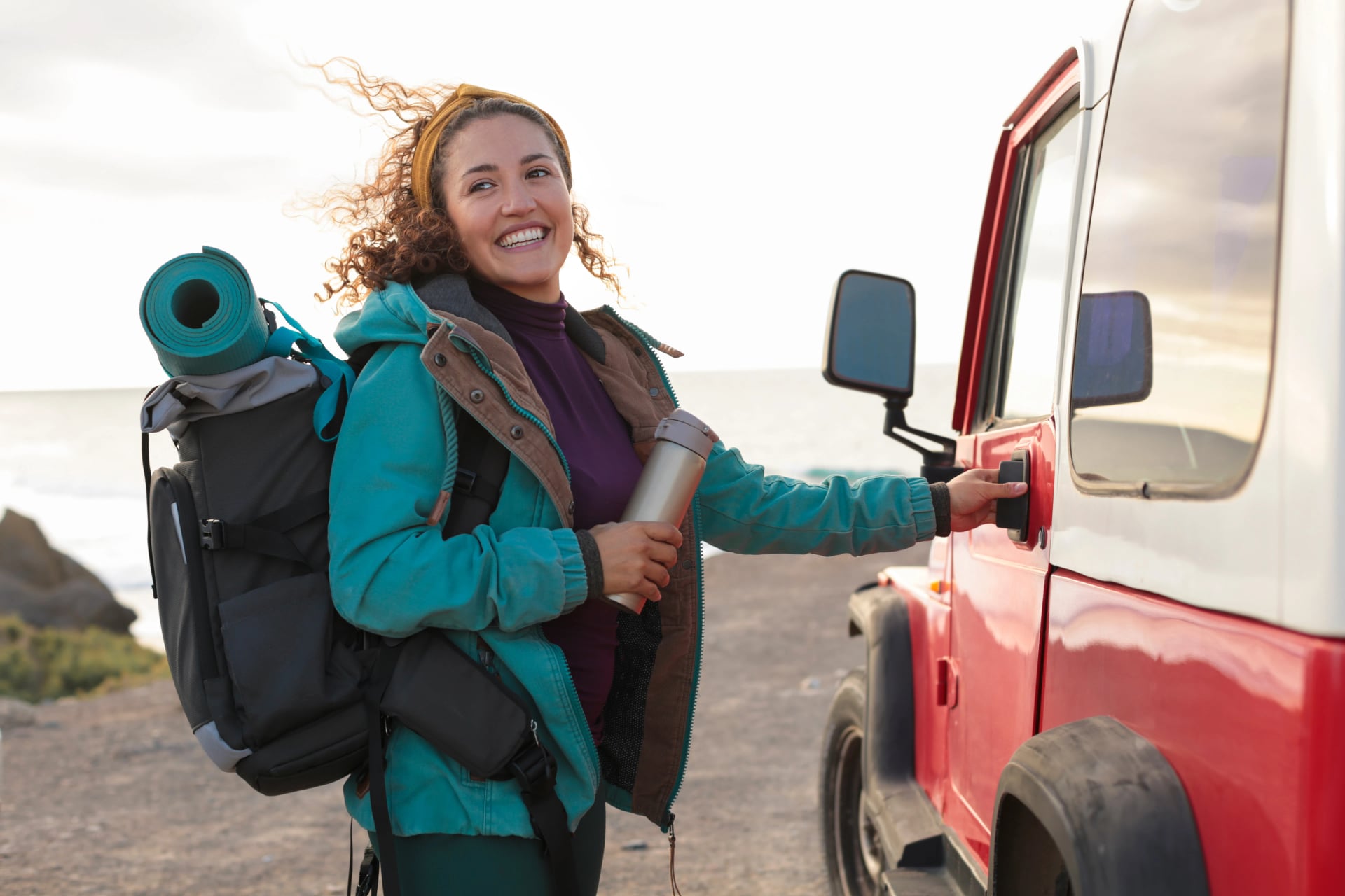 Beautiful young woman doing a road trip in the nature, driving an old off-road car