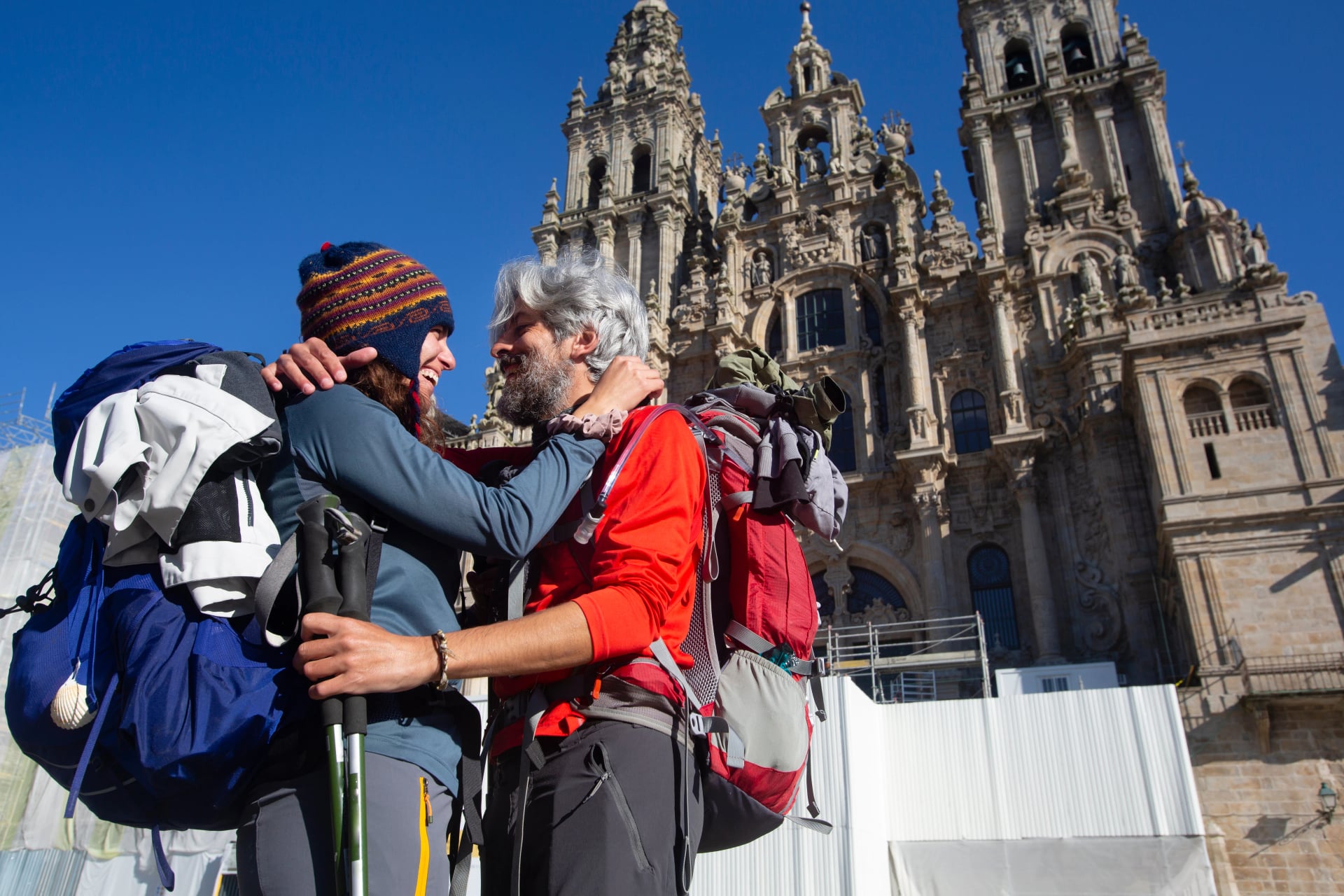A couple of pilgrims celebrate in front of the cathedral of Santiago that they have reached the end of the journey after walking the Camino de Santiago